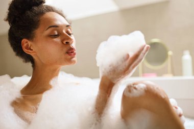 Bir kadın köpükle dolu bir küvette banyo yapıyor. Yüksek kalite