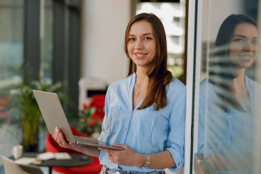 Modern bir iş yerinde, kendine güvenen bir iş kadını dizüstü bilgisayar üzerinde çalışırken profesyonelliğini gösterir.