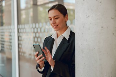 Modern ofiste akıllı telefon kullanan kendine güvenen bir iş kadını profesyonellik ve teknisyenlik becerileri sergiliyor.