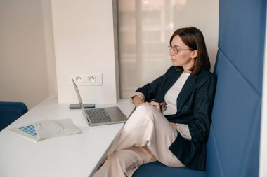 Ofisteki iş yerinde dizüstü bilgisayar kullanan profesyonel bir kadın. İş kıyafeti, gözlükler, verimlilik, odaklanma.