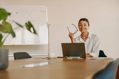 Kendine güvenen bir kadın şık bir ofis masasında modern profesyonelliği sergiliyor.