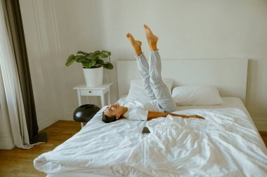 Bir insan rahat bir yatakta rahatlar, harika bir kaygısız anın tadını çıkarır ve pozitif enerji ve neşe saçar.