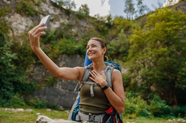 Neşeli bir yürüyüşçü, canlı bir doğa ortamında, maceranın ve doğanın özünü yakalayarak selfie çeker.