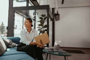 Şık bir ofiste profesyonel bir kadın, modern ve üretken bir yaşam tarzını sergileyen bir dizüstü bilgisayarla meşgul olur.