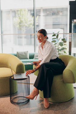 Şık giyinmiş yetenekli ve profesyonel bir kadın modern bir ofis ortamında çalışmalarına özenle daldı.