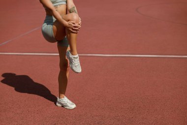 Sportif ve kendini işine adamış bir kadın, canlı ve parlak bir pistte dizlerini büker.