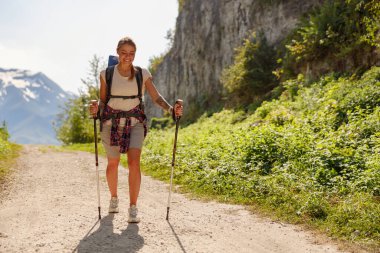 Hevesli bir yürüyüşçü, yemyeşil ve görkemli dağlarla çevrili çarpıcı manzaralı bir yolda ustaca yol alır.