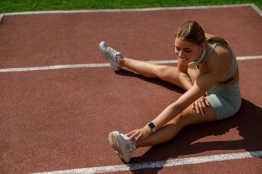 Genç bir atlet, yaklaşan antrenman seanslarına hazırlanmak için sahada geriniyor.