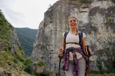 Neşeli bir kadın heyecan verici bir maceraya hazır bekliyor. Etrafında büyüleyici uçurumlar ve güzel doğayla çevrili.