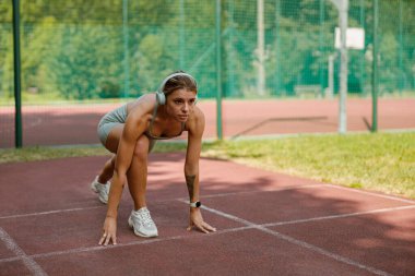 Yetenekli bir atlet pistte koşmaya hazırlanıyor. Gücünü ve kararsızlığını gösteriyor.