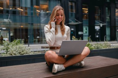 Çağdaş bir şehir ortamında, modaya uygun genç bir kadın etkin bir şekilde işine bir dizüstü bilgisayar kullanarak başlar.