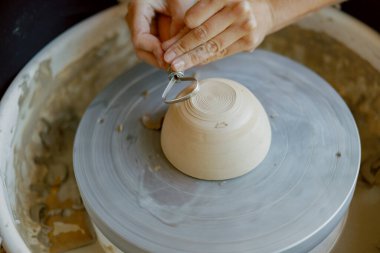 Çömlek çarkında kil şekillendiren yetenekli ellerin yakın çekimi, olağanüstü bir zanaatkarlık sergiliyor.