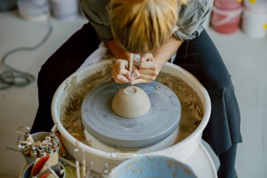 Yetenekli bir zanaatkar, canlı bir stüdyonun tekerindeki çömleği şekillendirir, zamanını ve uzmanlığını zanaata adamıştır.