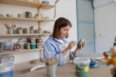 Çok yetenekli bir zanaatkar, canlı ve iyi döşenmiş bir çalışma alanında titizlikle güzel bir çömlek yapıyor.