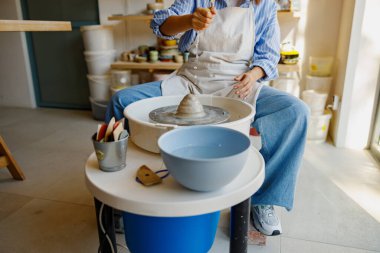 Huzurlu ve sakin bir stüdyo ortamında yetenekli bir çömlekçi dönen bir tekerleğin üzerinde yumuşak killeri titizlikle şekillendirir.