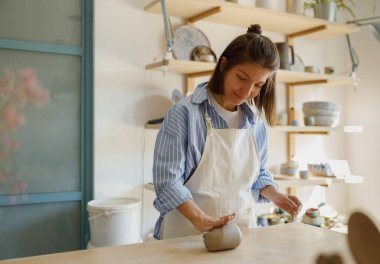 Parlak, havadar bir stüdyoda, yetenekli bir çömlekçi özenle yumuşak killeri şekillendirir, yaratıcılığını tam hareket halinde gösterir.