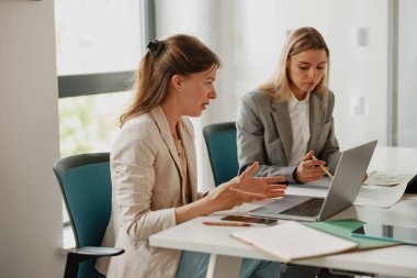 Bir şirket ofisinde, iki kadın bir toplantı sırasında düşünceli ve üretken bir tartışmaya girişirler.