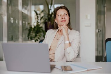 Çalışkan bir iş kadını, iyi düşünülmüş masasında derin düşüncelere dalmış, profesyonel bir çalışma alanını örnek gösteriyordu.