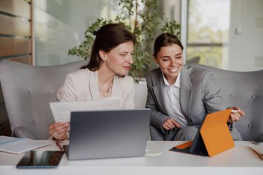 İki yenilikçi iş kadını modern ofis ortamında yaratıcı fikirler üretmekle meşgul.