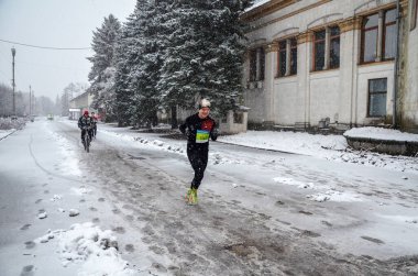 Maraton koşucuları şehir yolunda koşuyor. Sağlıklı yaşam tarzı, spor hobisi. Sokak kış maratonu, karlı açık hava koşusu, yarışma