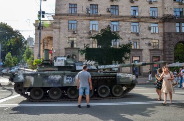 People walk among destroyed russian military tanks in central Kyiv, Ukraine
