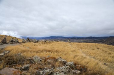 Resimli atmosferik Ermeni sonbahar dağ manzarası dağlık arazinin yumuşak yamaçları ve Güney Kafkasya 'nın sarı kuru otlarıyla dolu çayırlar.