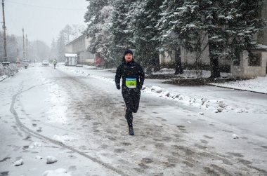 Sağlıklı sporcu, kış aylarında asfalt yolda şehir parkında koşuyor. Yaşam tarzı ve spor kavramları