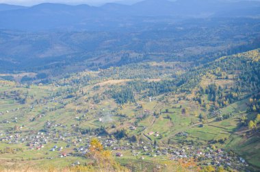 Vadinin aşağısındaki dağ köyünün güzel sonbahar manzarası, tepelerdeki evler ve tarım arazileri. Karpat Dağları, Ukrayna
