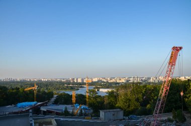 Ukrayna 'nın başkenti Kyiv' deki Dnipro nehrinin sol kıyısındaki konut binalarının arka planında inşaat vinci var.
