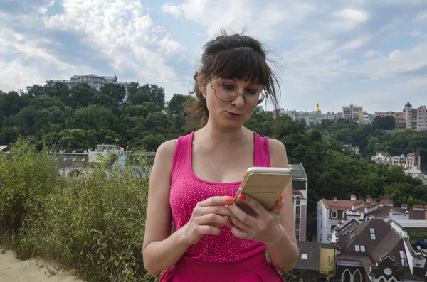 Mooi Meisje Met Bril Een Roze Jurk Kijken Naar Mobiele — Stockfoto