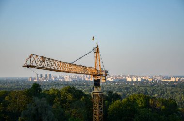 Şehir arka planına karşı sarı kule inşaat vinci. Sanayi yeni inşaat sektörü konsepti, şehir gelişimi