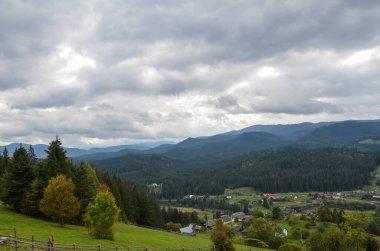 Vorokhta köyünün yukarıdan manzaralı kırsal manzarası orman dağlarını ve Ukrayna, Karpatlar 'daki vadiyi çevreleyen yeşil otlakları çevreledi.