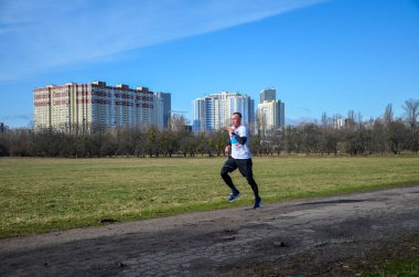 Sağlıklı sporcu, güneşli bir yaz gününde asfalt yolda şehir parkında koşuyor. Yaşam tarzı ve spor kavramları