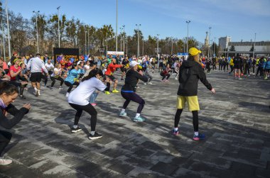 Bir grup koşucu maratonda koşmadan önce ısınıyor ve esniyorlar.