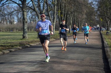 Maraton koşucuları şehir yolunda koşuyor. Sağlıklı yaşam tarzı, spor hobisi. Sokak maratonu, açık hava koşusu, yarışma
