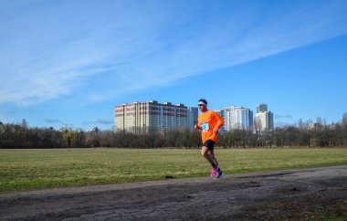 Koşucu yarışmasında koşan genç bir adamın görüntüsü. Koşu kıyafetli erkek sporcu dışarıda koşuyor..