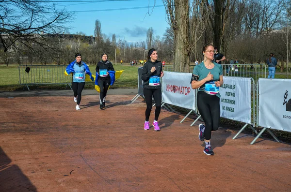 Genç dişiler maraton yarışında yarışıyorlar. Şehir parklarında ve caddelerde koşu yarışı.