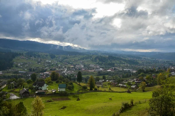 Vorokhta dağ köyünün panoramik manzarası. Yeşil tarlaları, ağaçları, evleri ve arka planda dağları olan kırsal alan. Karpat Dağları, Ukrayna.