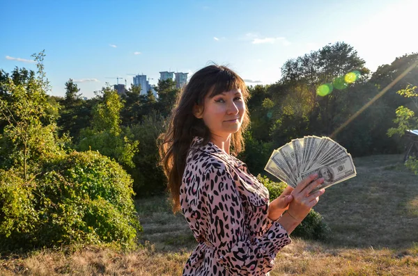 Gülümseyen genç bir kadının portresi nakit para, para, finansal başarı ve zenginlik kavramına hayrandır.