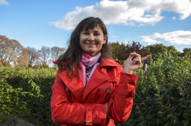 Kırmızı ceketli, gülümseyen ve elinde anahtarlarıyla gülümseyen esmer kadın. Araba ya da ev kirası