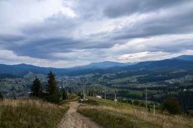 Bulutlu gökyüzünün altındaki vadide orman, dağlar ve Karpatya köyü manzarası 