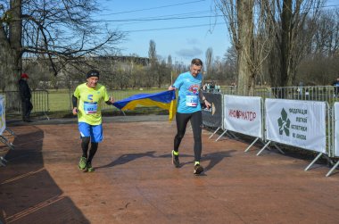 Koşucular Ukrayna bayrağını ellerinde tutarak, Rus askeri saldırılarına karşı Ukrayna 'yı desteklemek için bitiriyorlar.