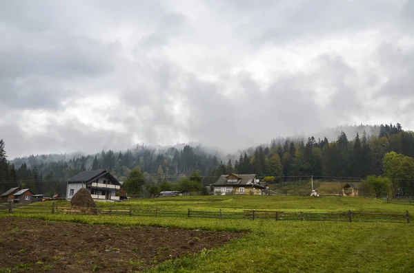 Sonbahar sisiyle kaplanmış ormanlı dağ sırtlarının yanındaki kır evleri. Karpat Dağları, Ukrayna