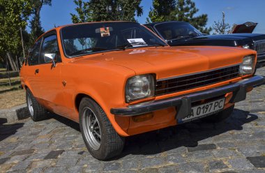 Orange two-door coupe subcompact araba Isuzu Gemini 1st gen (PF50), 1978 Opel Kadett 'in retro araba sergisinde sergilenen bir analogu.