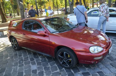 Caddeye park edilmiş kırmızı dört koltuklu Mazda MX-3 spor araba.