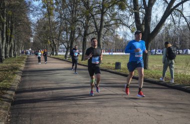 Bir grup koşucu dışarıda koşuyor. Kentsel alanda yarışan sportif insanlar, sağlıklı yaşam tarzı ve spor kavramları.