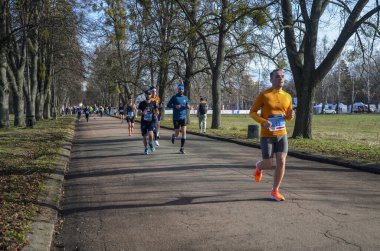 Bir grup koşucu dışarıda koşuyor. Kentsel alanda yarışan sportif insanlar, sağlıklı yaşam tarzı ve spor kavramları.