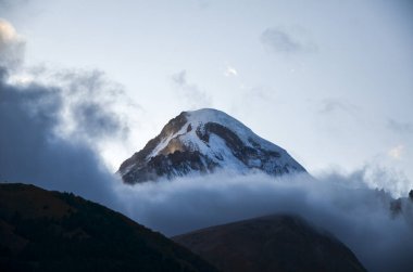 Kazbek Dağı 'nın karlı zirvesi Kazbegi, Stepantsminda, Georgia' dan görülen alçak bulutlarla kaplıydı.