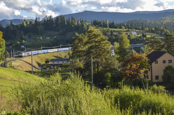 Güneşli bir sonbahar gününde, Vorokhta köyünün önünden tren geçen güzel bir dağ manzarası. Karpat Dağları, Ukrayna