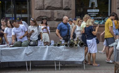 İnsanlar ödül kasklarına, el bombalarına ve Rus işgalcilerin ordusundan ele geçirilen diğer askeri eşyalara bakıyorlar.